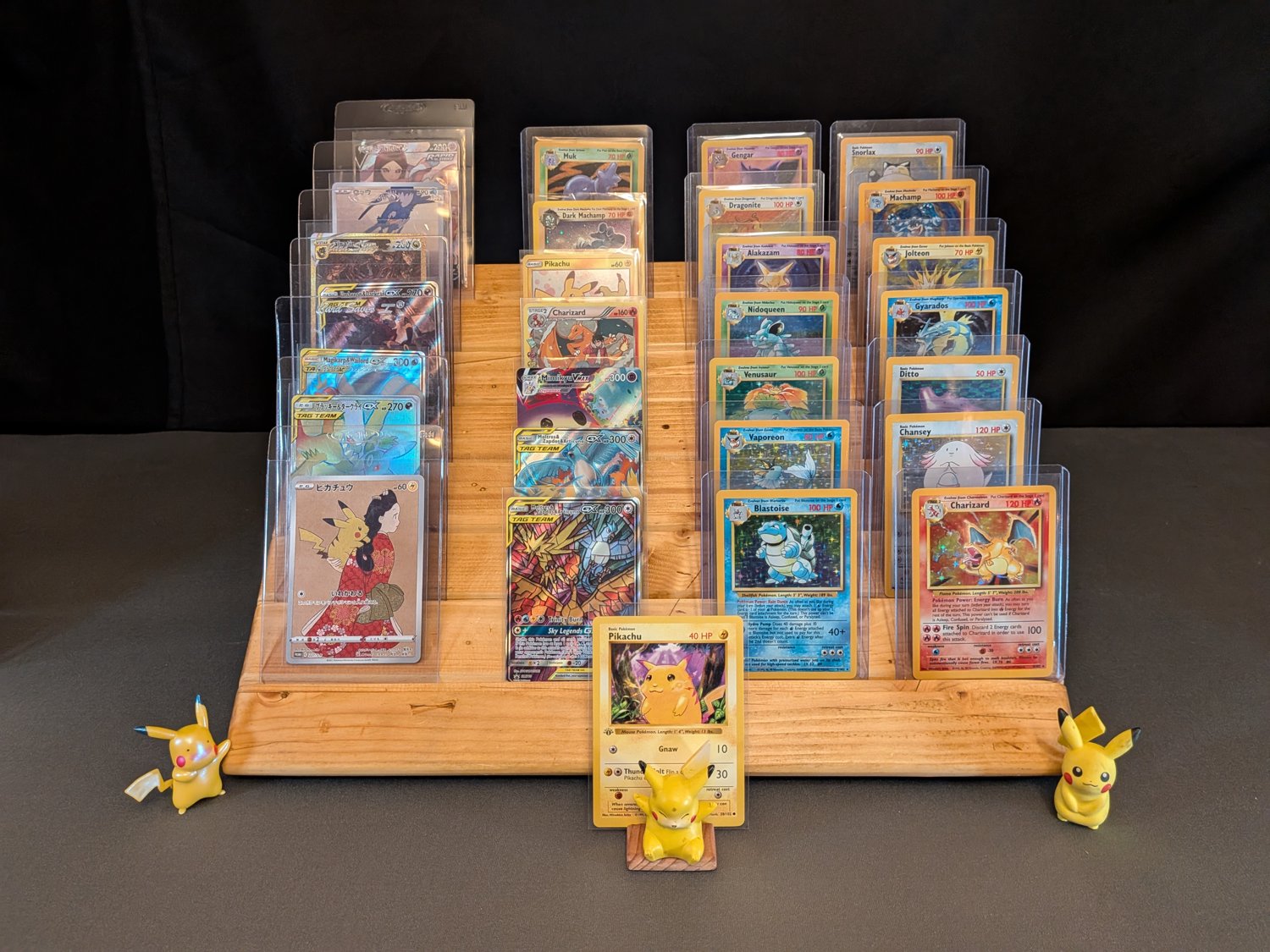 Vintage and modern Pokémon cards arranged on a wooden display with Pikachu figures