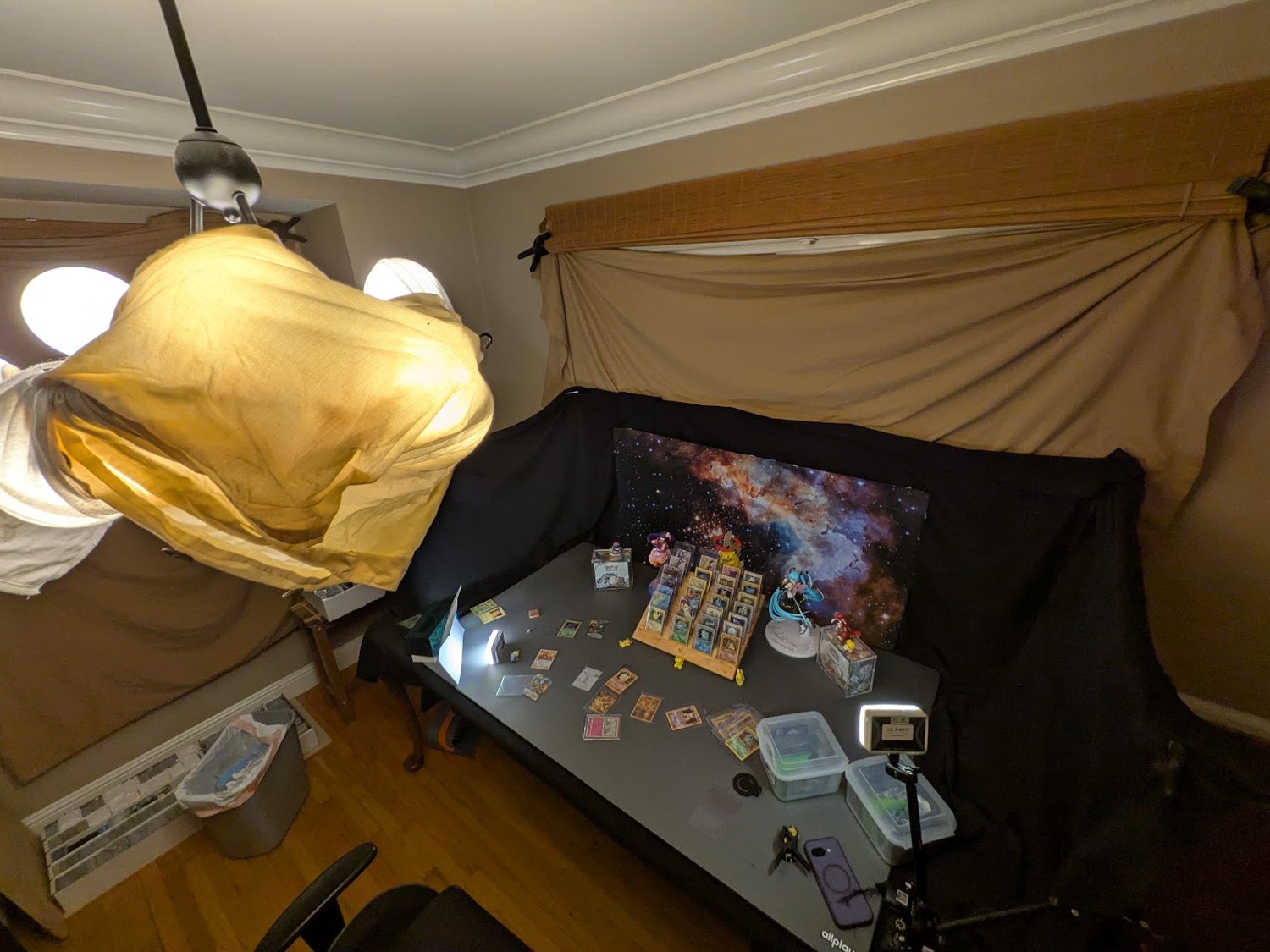 Behind-the-scenes card and figure photography setup with lights and a wooden display